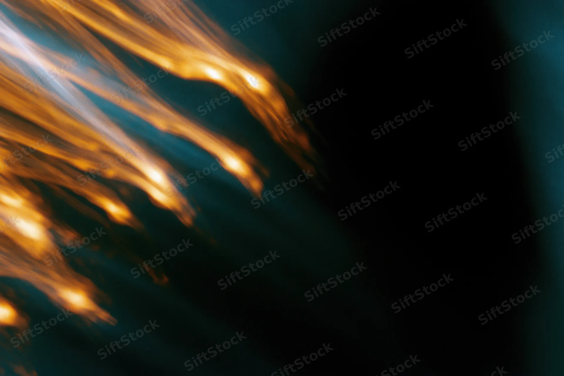 Warm amber light streaks moving diagonally across a dark background with soft blur and copyspace
