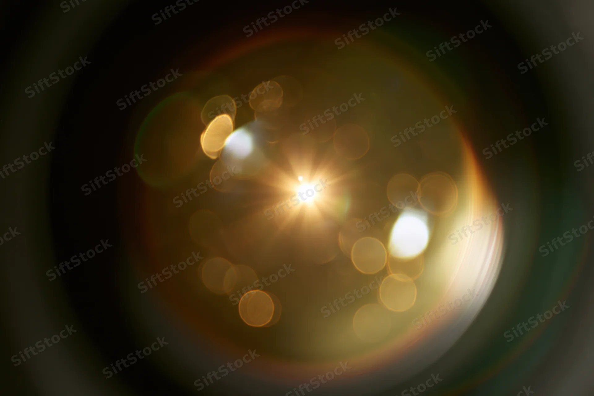 Close-up view into a camera lens showing light flares and bokeh circles