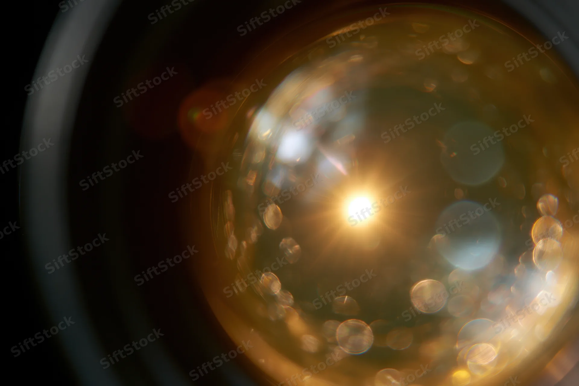 Extreme close-up view into a camera lens showing light reflections and bokeh effects