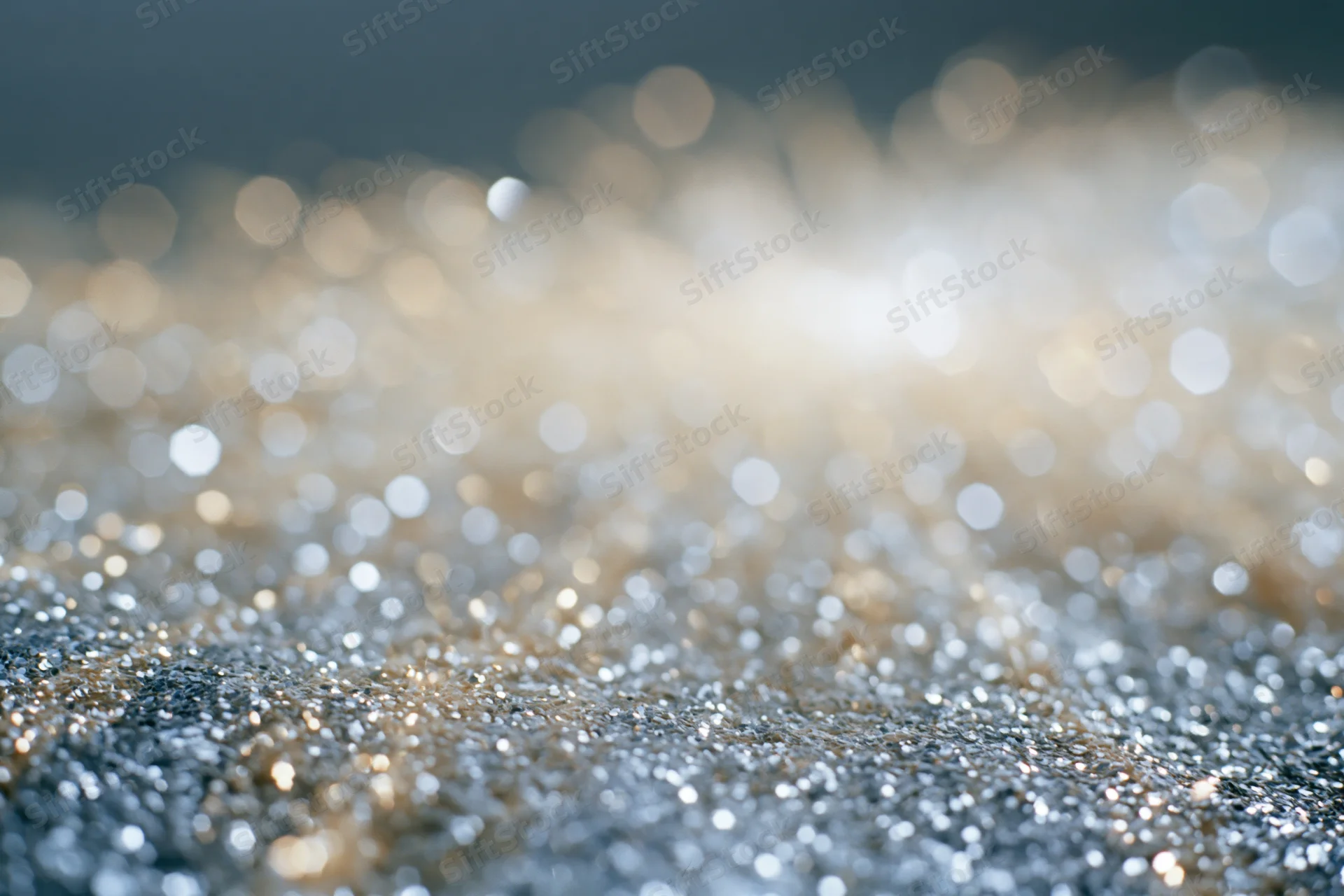 Glittering particles scattered across a textured surface with bokeh lights in the background
