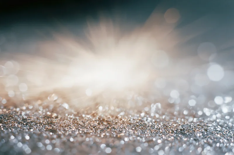 Glittering surface with bright light burst and bokeh effect in abstract background