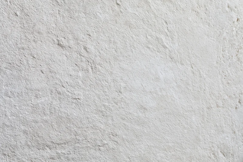 Flat concrete wall surface filling the frame with rough texture and neutral gray tone