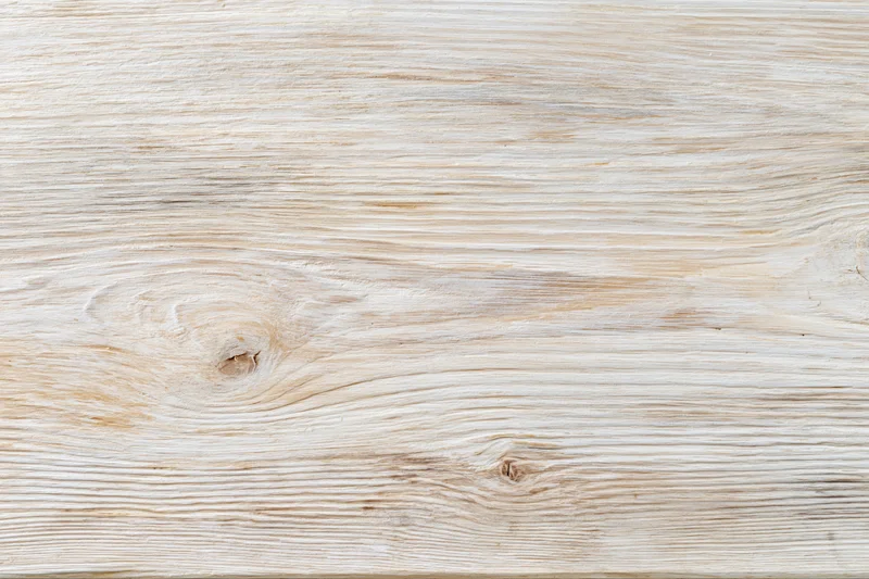 Whitewashed wooden board surface with visible grain and knots in flat lay closeup