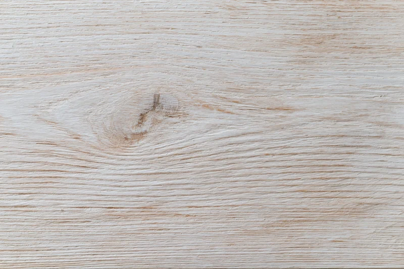 Close-up of a whitewashed wooden board surface with visible grain and knot, flat lay arrangement
