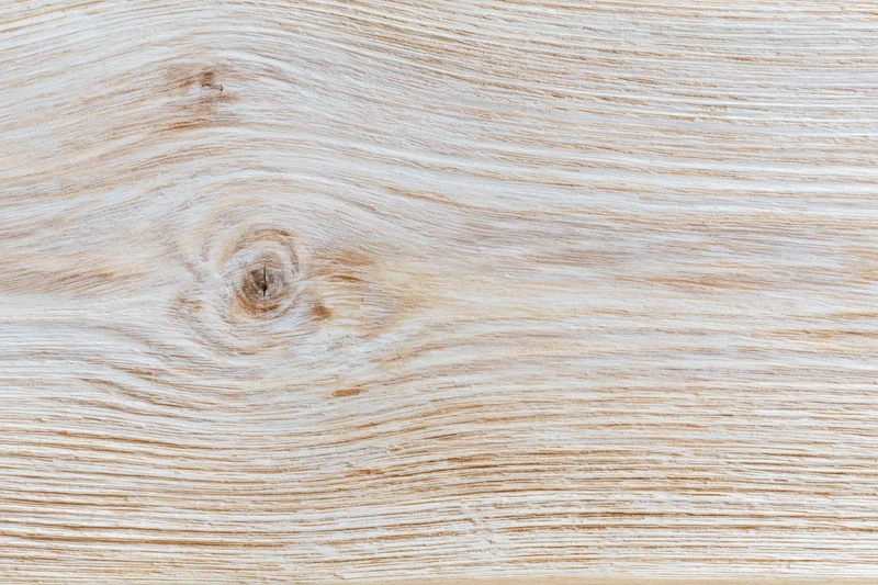 Whitewashed wooden board surface with visible grain and knot in flat lay closeup