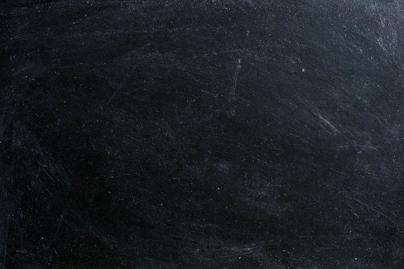 Worn black chalkboard surface with smudged chalk residue and scratches, flat lay close-up