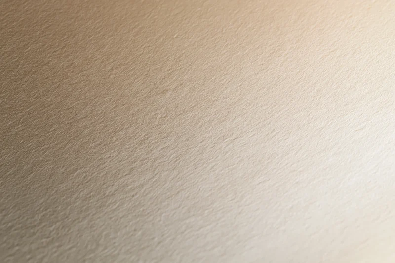 Close-up of smooth cream-colored paper surface with subtle texture and even lighting