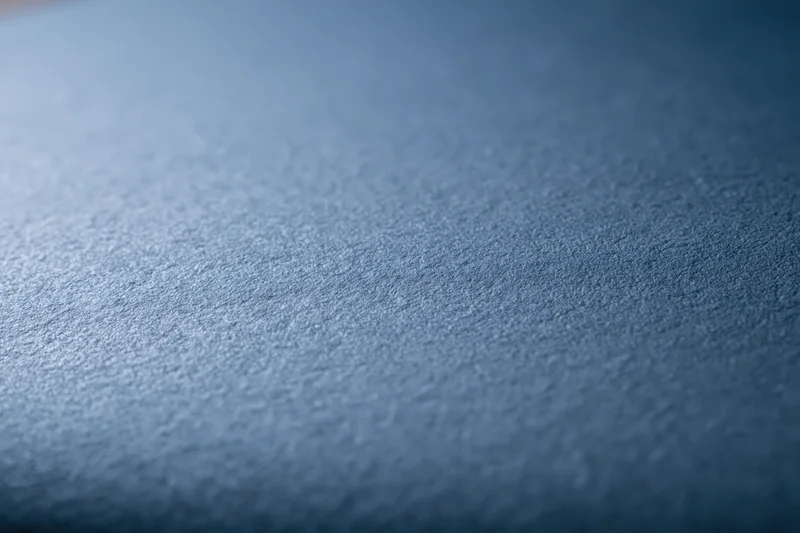 Flat matte steel-blue textured surface filling the frame as a background