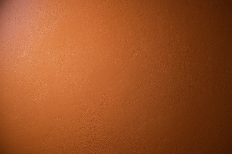 Flat orange painted wall surface filling the frame as a textured background