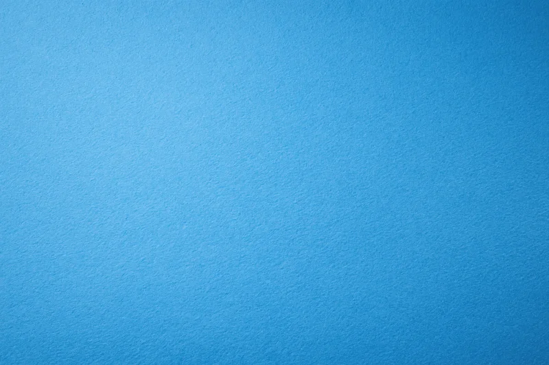 Solid blue paper or painted wall surface filling the frame as a uniform background