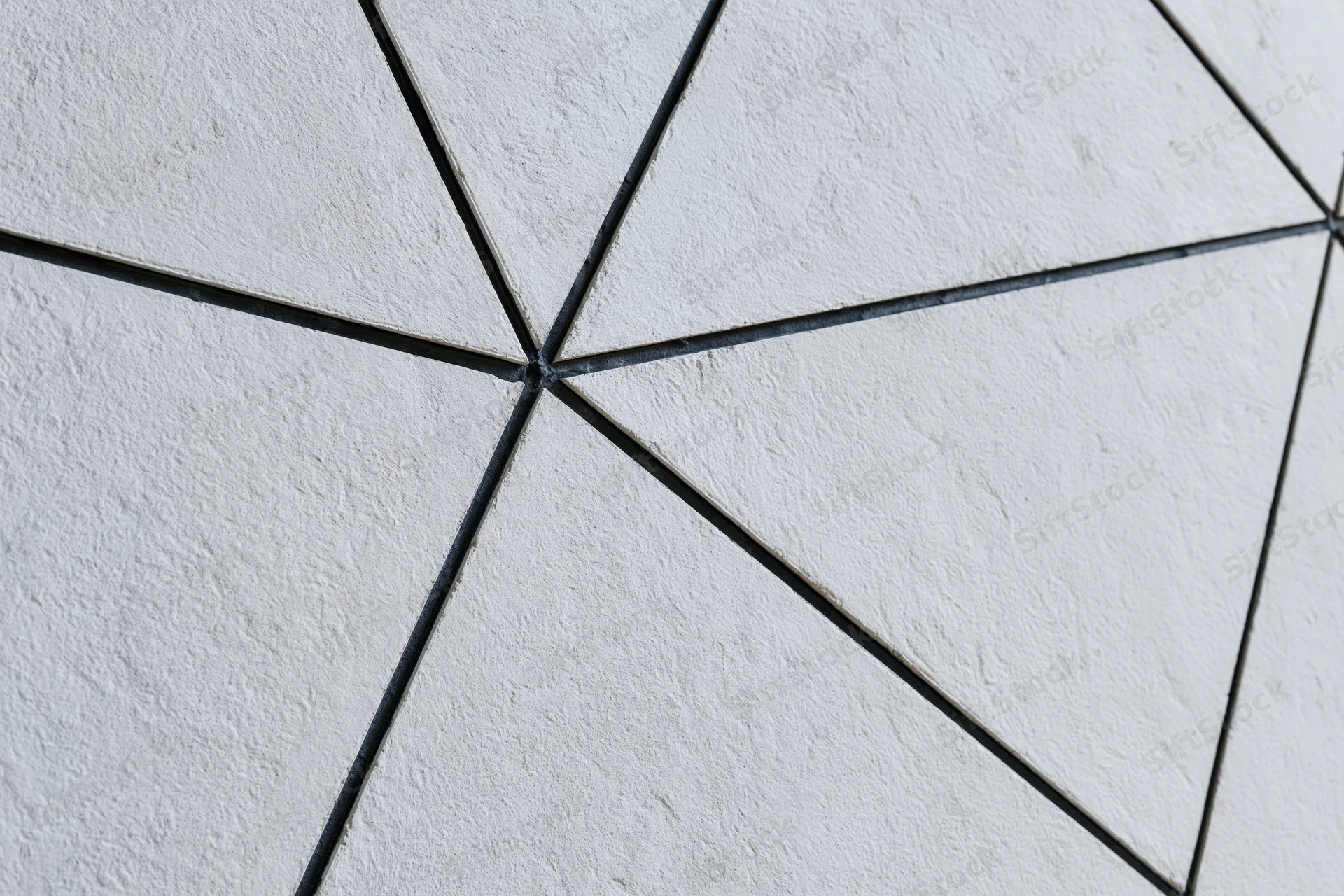 Textured concrete wall divided into irregular triangular sections by dark grout lines