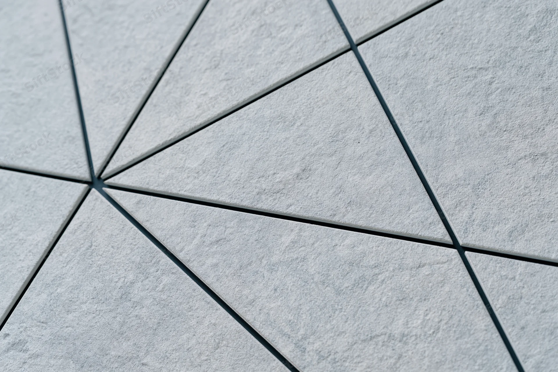 Textured concrete wall divided into irregular triangular sections forming a geometric pattern