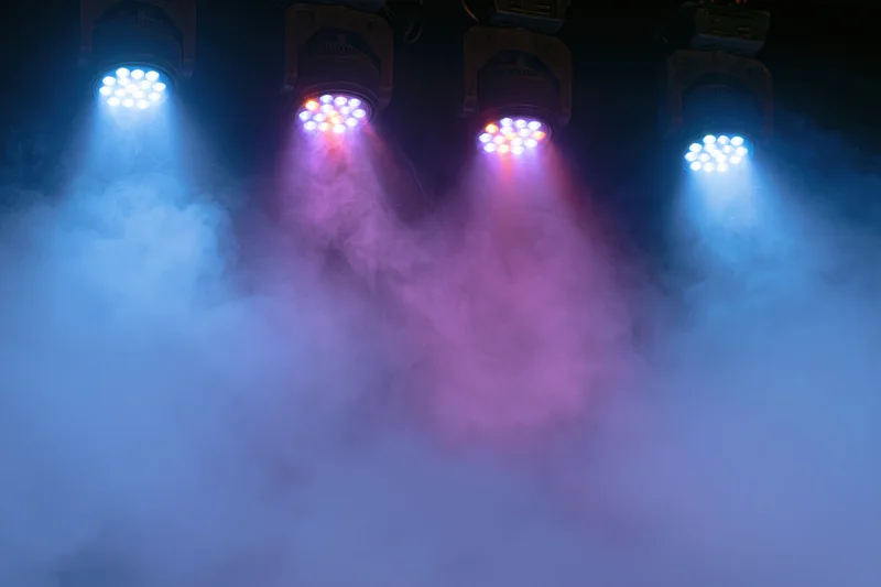 Four led par can stage lights mounted overhead shining down through colored smoke