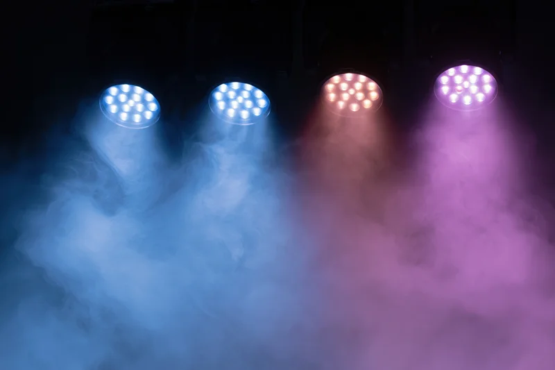 Four led par can stage lights mounted overhead shining down through colored smoke