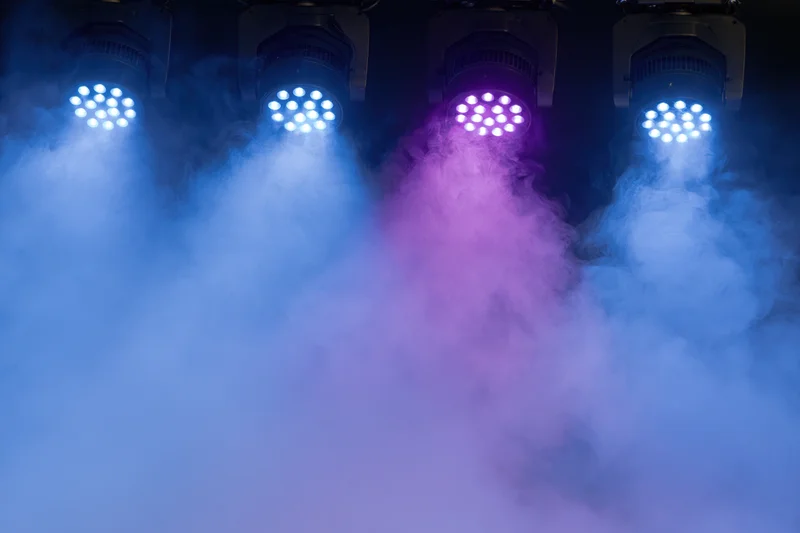 Four led par can stage lights mounted overhead shining down through colored smoke