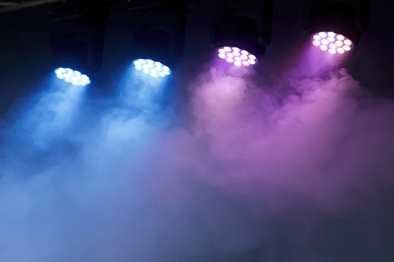 Four led par can stage lights mounted overhead shining down through colored smoke