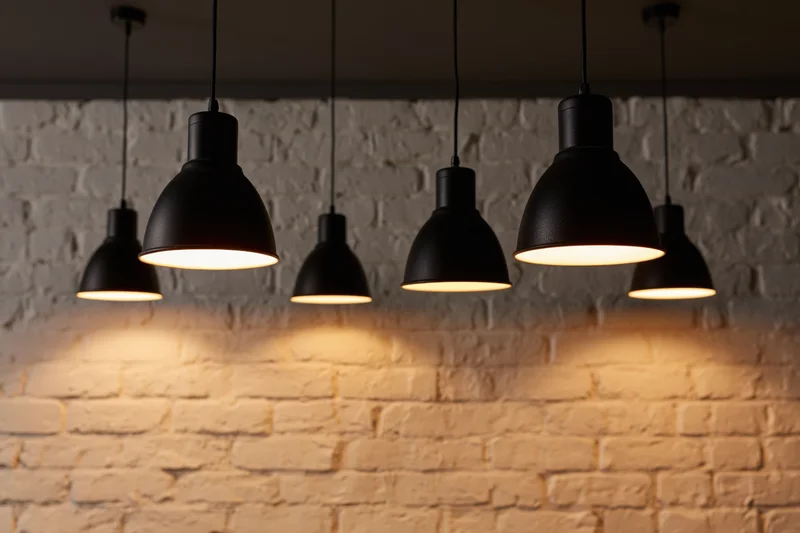 Black industrial pendant lights hanging from ceiling above white brick wall