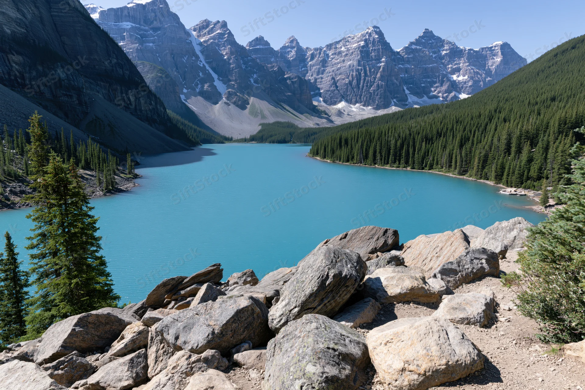Glacial turquoise lake nestled in rocky mountain valley surrounded by pine forest and snow-capped peaks