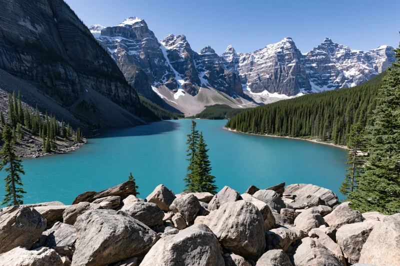 Glacial turquoise lake nestled in rocky mountain valley surrounded by snow-capped peaks and pine forest
