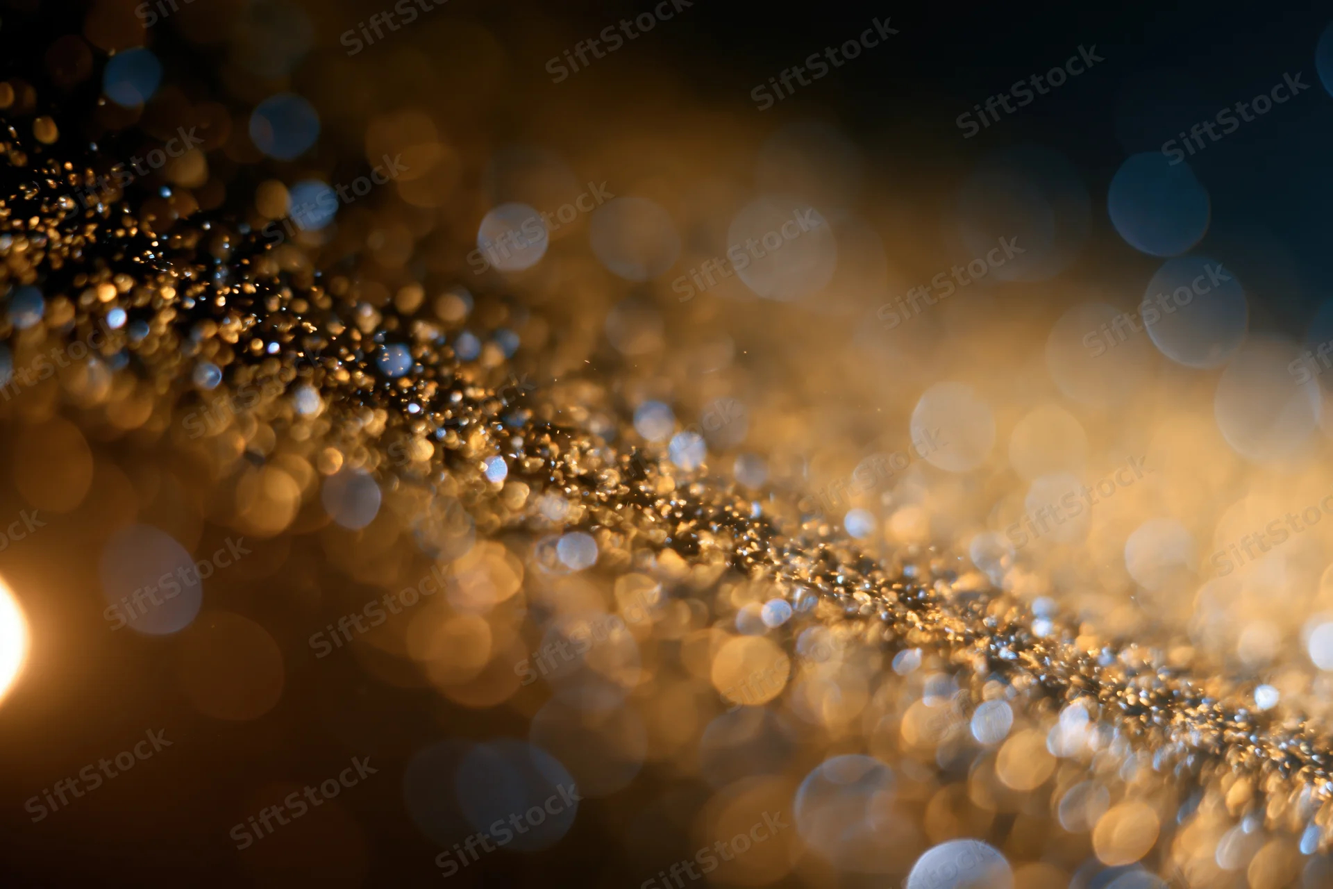 Gold dust particles suspended mid-air with bokeh light orbs in warm ambient glow