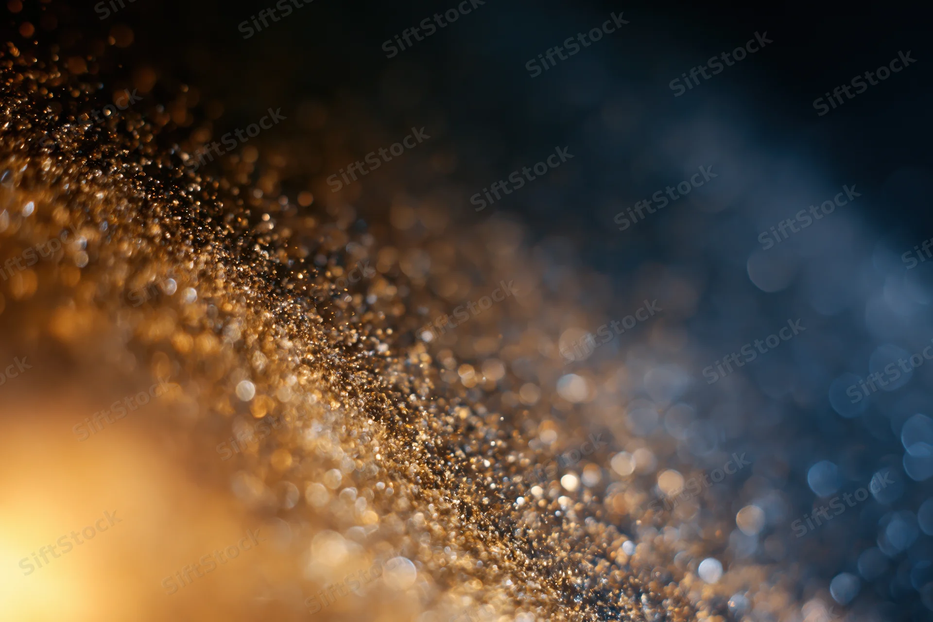 Gold dust particles suspended mid-air with bokeh light orbs in a gradient background