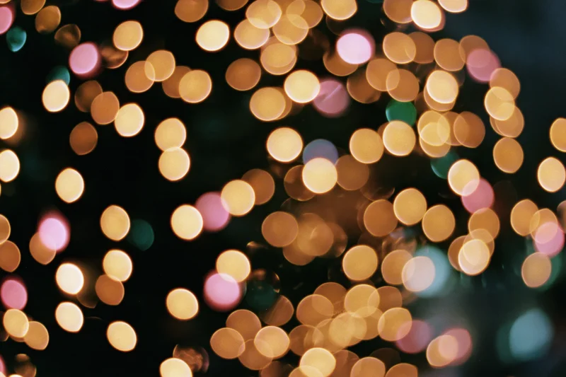 Defocused christmas tree lights glowing in warm bokeh against dark night background