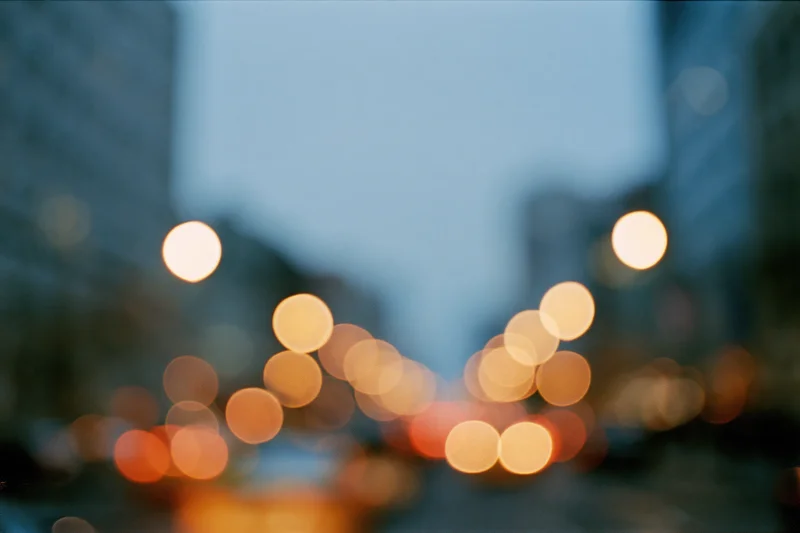 Defocused city street at dusk with blurred bokeh lights from traffic and buildings