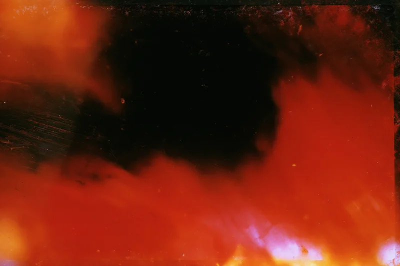 Abstract analog photograph with heavy light leaks and underexposure showing red, black, and orange hues
