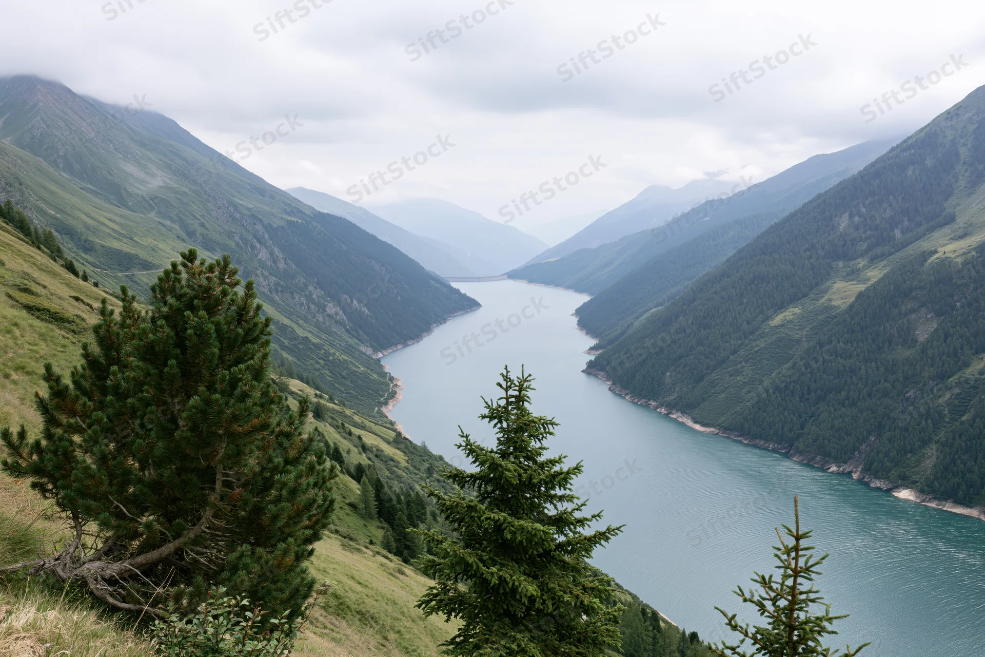 High-altitude reservoir nestled between steep green mountains under cloudy sky