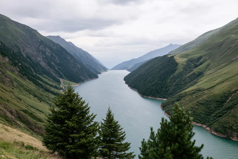 High-altitude reservoir nestled between steep green mountains under cloudy sky