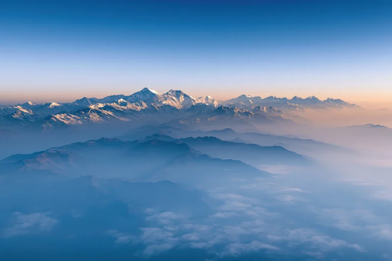 High himalayan peaks rising above a thick sea of mist at sunrise