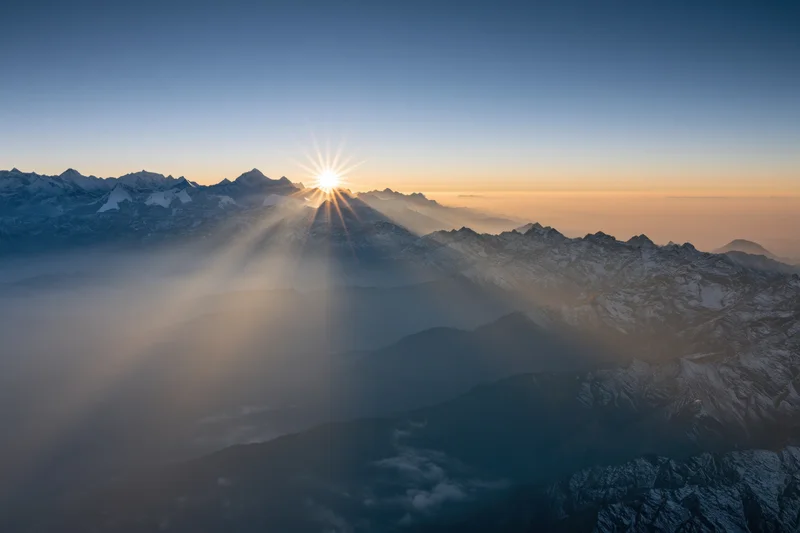 High Himalayan peaks rising above a thick sea of mist at sunrise