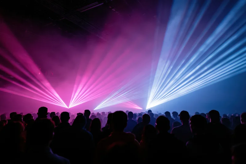 Dense crowd of silhouettes facing stage with laser lights in nightclub