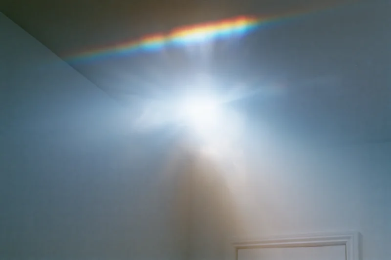 Intense lens flare and light leak across a white wall and ceiling in a room corner