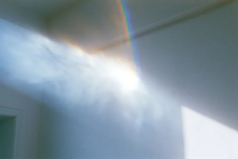 Intense lens flare and light leak across a white wall and ceiling in an interior room