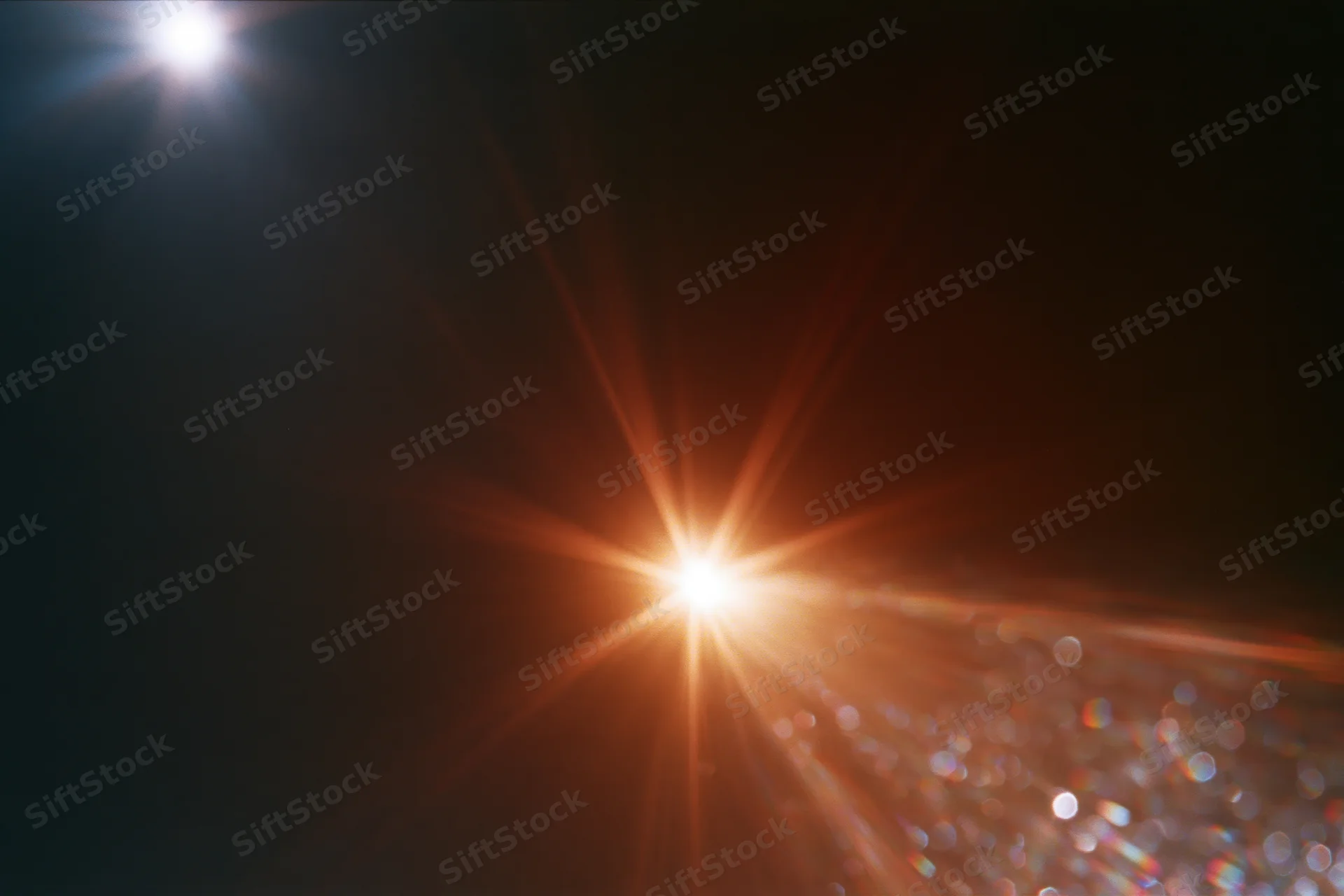 Intense lens flare from a bright light source with bokeh highlights against a dark background