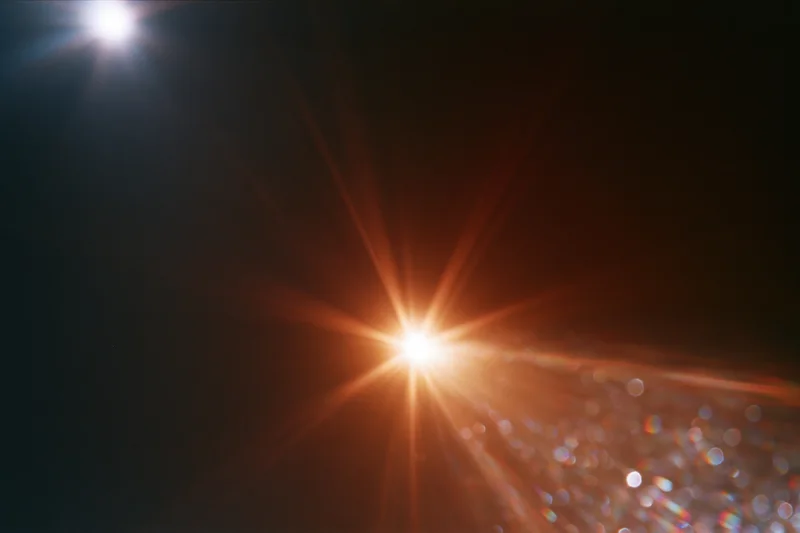 Intense lens flare from a bright light source with bokeh highlights against a dark background
