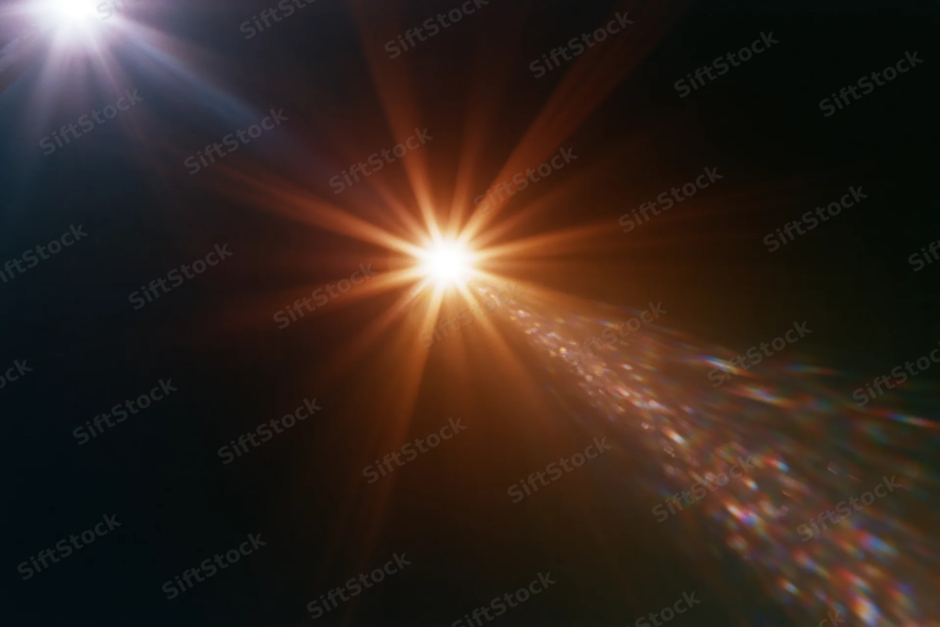 Intense lens flare from a bright light source radiating starburst rays across dark background with colorful light dispersion