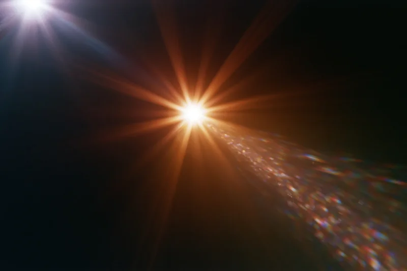 Intense lens flare from a bright light source radiating starburst rays across dark background with colorful light dispersion