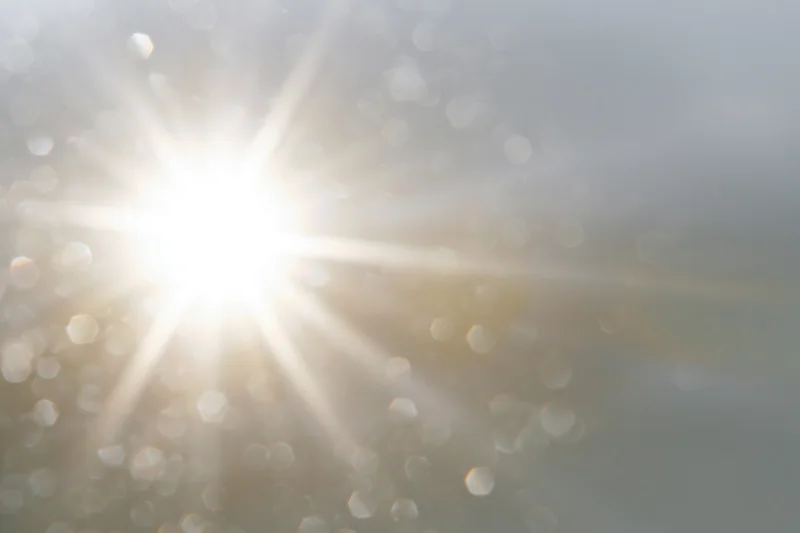 Intense sun flare bursting from center-left with soft bokeh and diffused light across sky