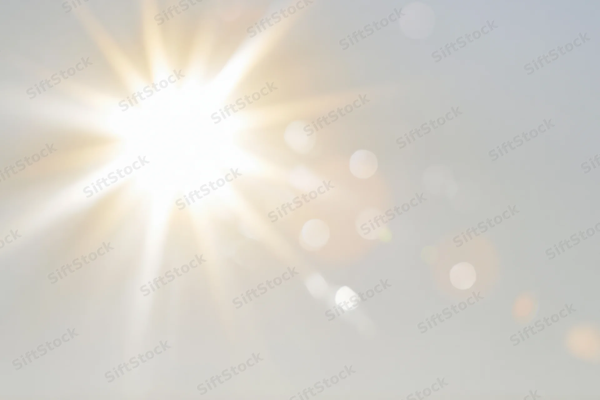Intense sun flare bursting from center-left against a bright sky with soft bokeh highlights and copyspace