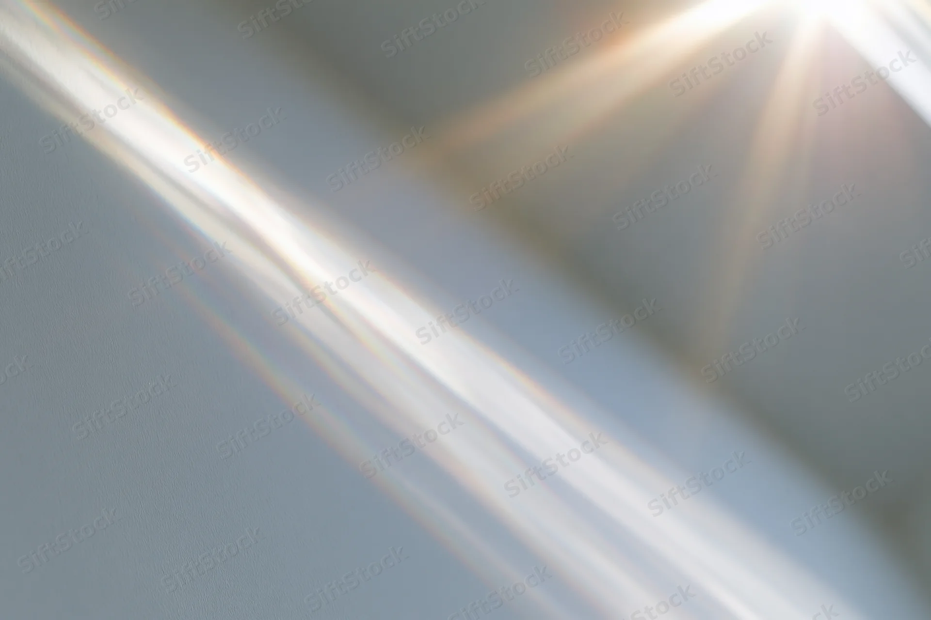 Sunlight rays streaming through a window onto a pale wall indoors