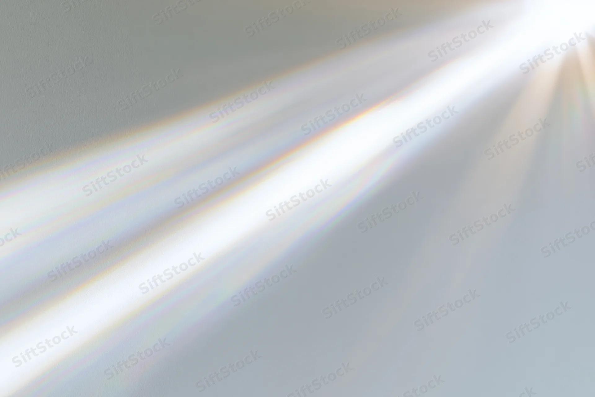 Sunlight rays streaming through a window onto a pale interior wall