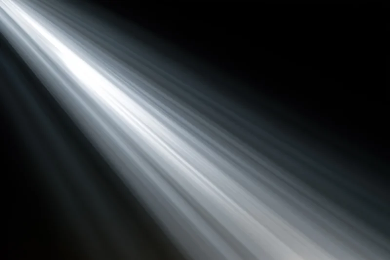 Intense white light rays radiating diagonally from upper left corner against dark background