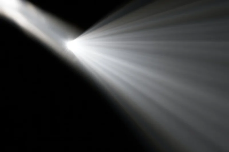 Intense white light rays radiating diagonally from upper-left corner against dark background