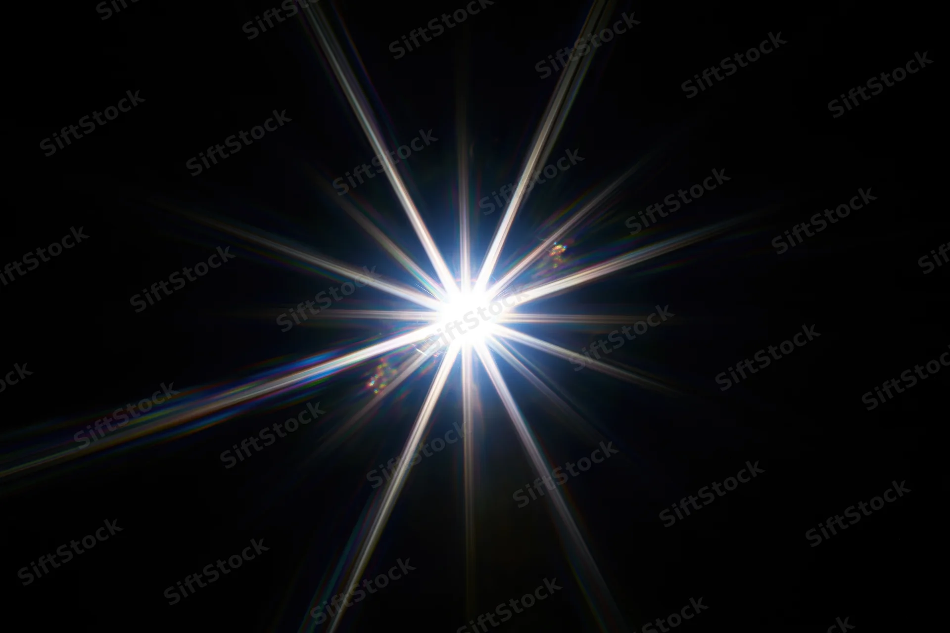 Intense white starburst lens flare centered against a pure black background