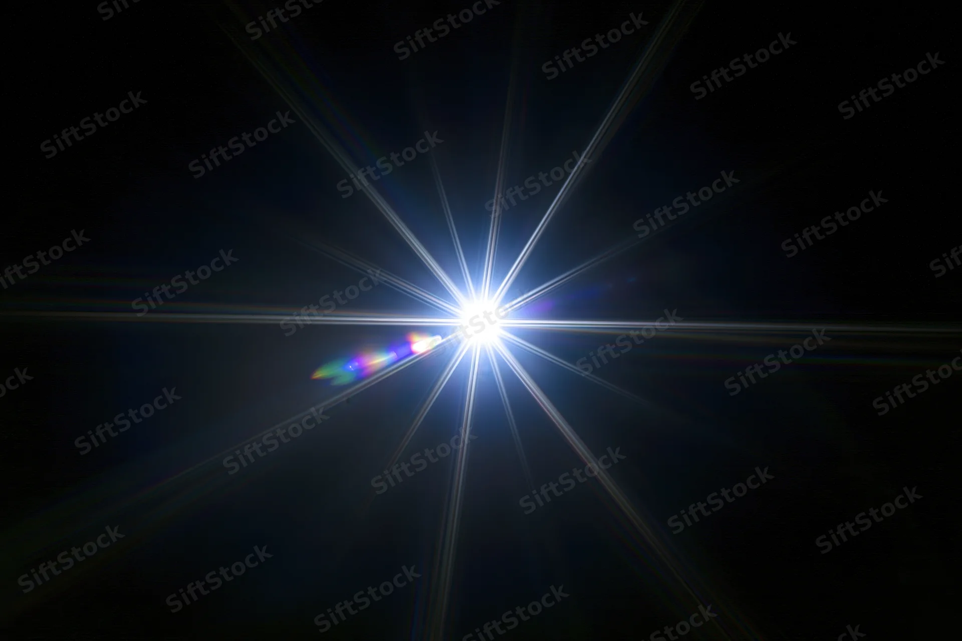 Intense white starburst lens flare centered against a pure black background with radial light beams and chromatic dispersion on one side
