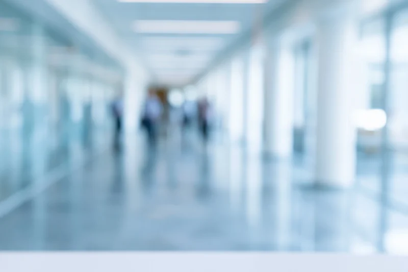 Blurred interior corridor of a modern office with people walking in the distance