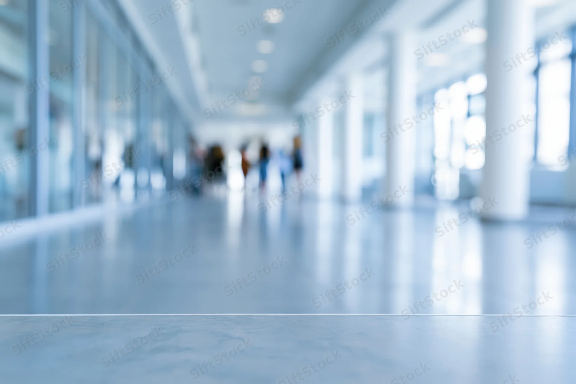 Defocused view of a modern office corridor with blurred people walking in the distance