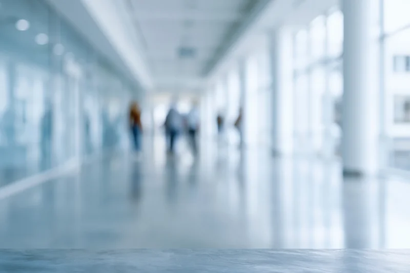 Blurred interior of modern office corridor with people walking in the distance